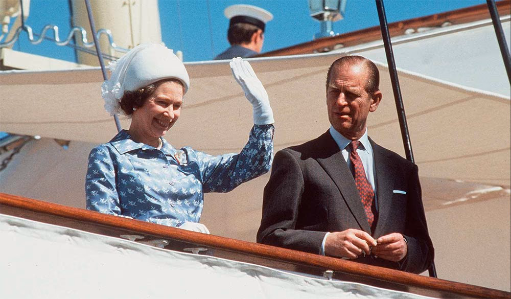 A royal couple waving from the deck of a ship