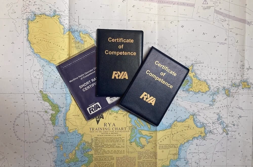 RYA Certificate of Competence and Short Range Certificate booklets on a nautical chart